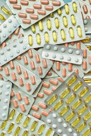 Une variété de pilules et de capsules emballées dans des plaquettes thermoformées en argent, gros plan.