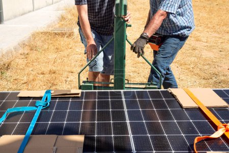 Trabajadores preparando una grúa para levantar una pila de paneles solares en el techo