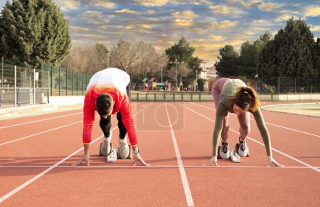 Photo for A man and a woman leaving the starting block at the athletics track. - Royalty Free Image