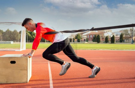 Photo for A young man trains power output in athletics with an elastic band - Royalty Free Image