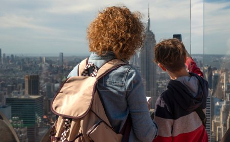 Mit Blick auf die weitläufige Skyline genießt eine Familie einen Panoramablick auf New York City mit dem Empire State Building im Zentrum.