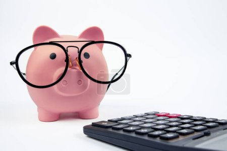 Glasses piggy bank with calculator on white background