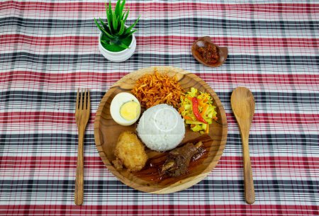 Photo for Red spiced chicken rice with pickled cucumber and carrots, boiled egg, potato fritters and sweet spiced fried potatoes. - Royalty Free Image