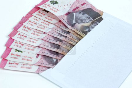 Indonesian rupiah currency. White envelope containing IDR 100,000 in cash isolated on white background