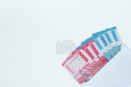 Roupie indonésienne monnaie. Enveloppe blanche contenant 100 000 IDR et 50 000 IDR en espèces isolées sur fond blanc