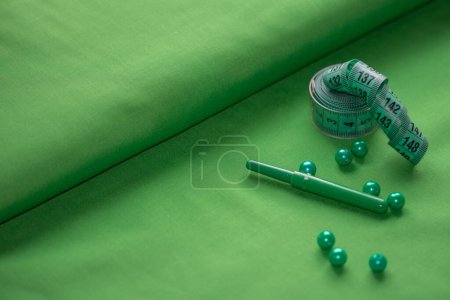 Téléchargez les photos : Accessoires de seving dans les tons verts sur un fond de tissu - en image libre de droit