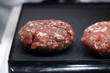 Foto de Carne de hamburguesa redonda cruda en plancha preparada para cocinar - Imagen libre de derechos
