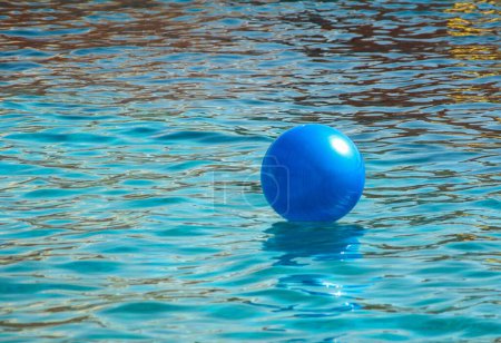 Téléchargez les photos : Grande boule gonflable bleue rebondissant sur l'eau calme. Une image évoquant une atmosphère détendue au bord de la mer. - en image libre de droit