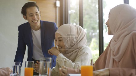 Foto de Un grupo de exitosos amigos musulmanes asiáticos ascendentes disfrutan de una tranquila cafetería reuniéndose en un día soleado brillante y alegre - Imagen libre de derechos