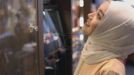 Téléchargez les photos : Gros plan Portrait d'une jeune femme musulmane asiatique vêtue du traditionnel hijab regardant la caméra souriant avec confiance sur un fond blanc - en image libre de droit