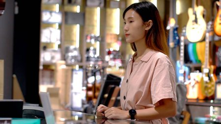 Téléchargez les photos : Jeune femme asiatique utilisant smartwatch pour acheter des produits au terminal de point de vente dans un magasin de détail avec communication en champ proche technologie de paiement d'identification par radiofréquence nfc - en image libre de droit