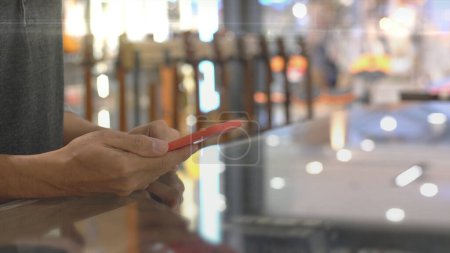 Photo for An upwardly mobile Asian Muslim man using a mobile phone to pay for a product at a sale terminal with nfc identification payment for verification and authentication - Royalty Free Image