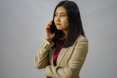 Photo for Portrait of a young Asian business woman talking on mobile phone, studio shot, business concept, isolated background - Royalty Free Image