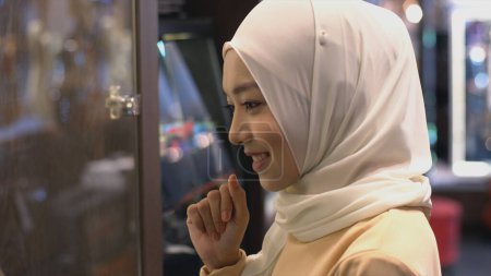 Téléchargez les photos : Gros plan Portrait d'une jeune femme musulmane asiatique vêtue du traditionnel hijab regardant la caméra souriant avec confiance sur un fond blanc - en image libre de droit