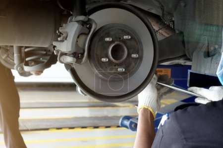 Téléchargez les photos : Un mécanicien répare, meule le disque de frein et remplace les plaquettes de frein dans une station-service d'un atelier de réparation automobile - concept de sécurité du véhicule - en image libre de droit