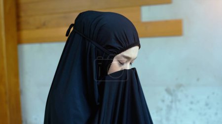 Téléchargez les photos : Portrait d'une femme musulmane asiatique dans une prière quotidienne à la maison récitant le passage de la Sourate al-Fatiha du Coran dans un seul acte de Sujud appelé une Sajdah ou prosternation - en image libre de droit