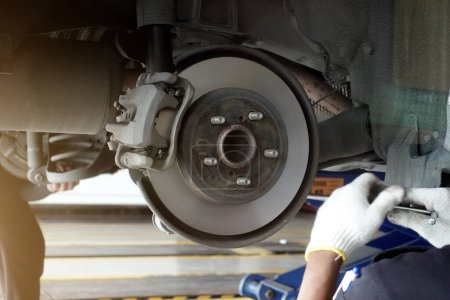 Téléchargez les photos : Un mécanicien répare, meule le disque de frein et remplace les plaquettes de frein dans une station-service d'un atelier de réparation automobile - concept de sécurité du véhicule - en image libre de droit