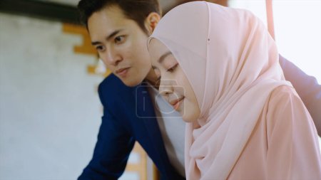 Photo for Upwardly mobile Asian Muslim business entrepreneur SME start up young man and women discussing sale and marketing analysis, Asian Muslim SME teamwork e-commerce concept - Royalty Free Image