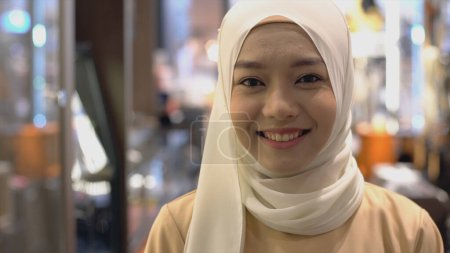 Foto de Acercamiento Retrato de una joven musulmana asiática vestida con el tradicional Hijab mirando a la cámara sonriendo con confianza sobre un fondo blanco - Imagen libre de derechos