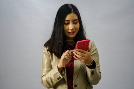 Photo for Portrait of a young Asian business woman with mobile phone, studio shot, business concept, isolated background - Royalty Free Image
