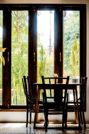 Foto de Un acogedor restaurante con luz de la mañana que atraviesa la ventana, creando un ambiente cálido en una pequeña mesa para dos personas junto a la ventana - Imagen libre de derechos