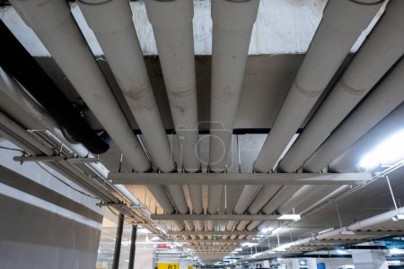 Téléchargez les photos : Système de tuyauterie souterrain dans un immeuble de bureaux parking offrant de l'eau douce, des égouts, de l'électricité et du gaz aux bureaux et aux ateliers au-dessus - en image libre de droit