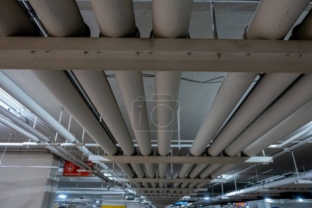 Photo for Underground piping service system in an office building car parking delivering fresh water, sewage, electrical and gas to the offices and shop floors above - Royalty Free Image