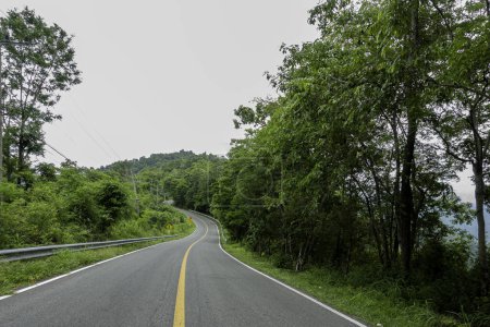 Foto de Campiña carretera que pasa a través de la vegetación exuberante serena y follaje tropical selva tropical paisaje de montaña en la montaña Doi Phuka reserva el parque nacional del norte de Tailandia - Imagen libre de derechos