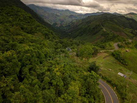 Photo for Logistic concept aerial view of countryside road - motorway passing through the serene lush greenery and foliage tropical rain forest mountain landscape - Royalty Free Image