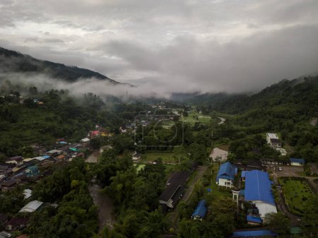 Photo for Aerial view of a village in the lush green rain cloud cover tropical rain forest mountain during the rainy season on the Doi Phuka Mountain reserved national park the northern Thailand - Royalty Free Image