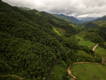 Téléchargez les photos : Vue aérienne d'un village dans la luxuriante couverture nuageuse de pluie verte forêt tropicale montagne pendant la saison des pluies sur la montagne Doi Phuka réserve parc national du nord de la Thaïlande - en image libre de droit