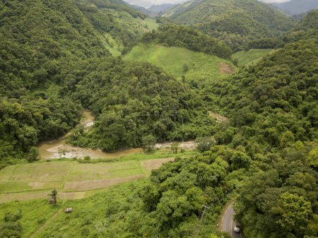 Téléchargez les photos : Vue aérienne d'un village dans la luxuriante couverture nuageuse de pluie verte forêt tropicale montagne pendant la saison des pluies sur la montagne Doi Phuka réserve parc national du nord de la Thaïlande - en image libre de droit