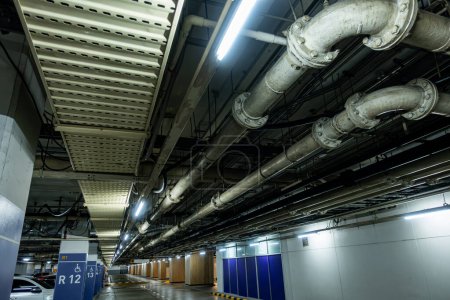 Photo for Pipelines in the underground parking of a petroleum and gas refinery run along the ceiling, servicing the industrial complex - Royalty Free Image