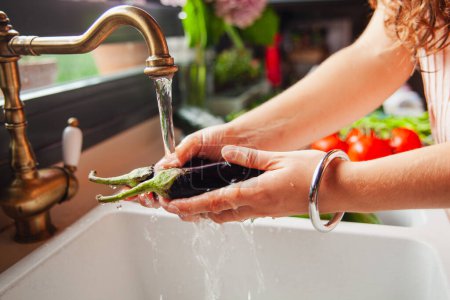 Téléchargez les photos : Détail du lavage des mains d'une femme aubergine sous le robinet de la cuisine - en image libre de droit