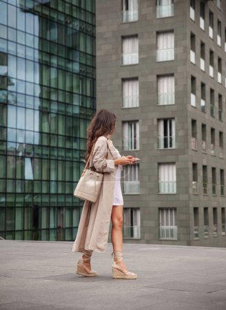 Téléchargez les photos : Jeune fille urbaine dans un immeuble d'affaires marchant avec le téléphone à la main - en image libre de droit