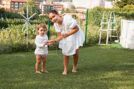 Photo for TWO LITTLE GIRLS SISTERS PLAYING IN THE GARDEN MAKING BUBBLES - Royalty Free Image