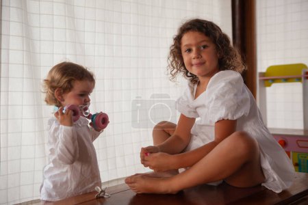 Téléchargez les photos : Deux filles sœurs jouant à la maison divertissant - en image libre de droit
