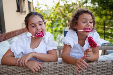 Foto de Dos niñas divirtiéndose con golosinas en el porche delantero en casa - Imagen libre de derechos
