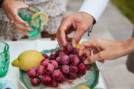 Photo for Tray of grapes and lemons with hands eating them - Royalty Free Image