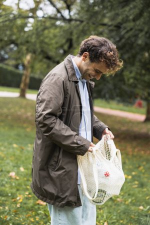 Téléchargez les photos : Jeune garçon souriant avec le sac de recyclage en plastique dans le parc, photo verticale - en image libre de droit