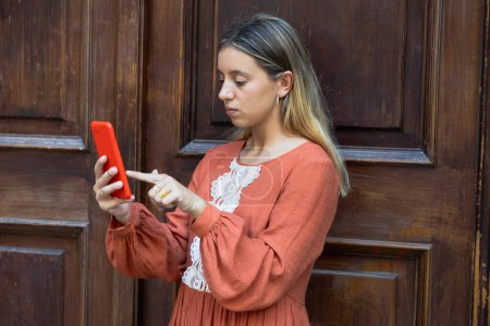 Photo for Young girl on the street checking her cell phone - Royalty Free Image