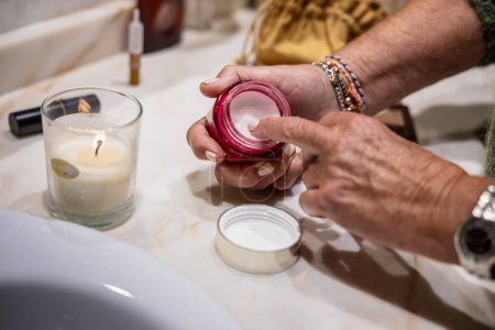 Foto de Detalle de la mano de la mujer tomando crema hidratante del frasco para aplicarlo - Imagen libre de derechos