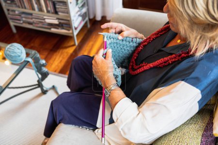 Téléchargez les photos : Découpe d'une femme tricotant un pull vert avec ses mains dans un plan à tricoter plat - en image libre de droit