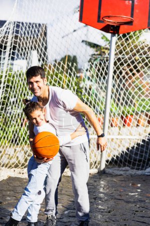 Foto de Padre e hija abrazándose sonriendo con baloncesto, foto vertical - Imagen libre de derechos