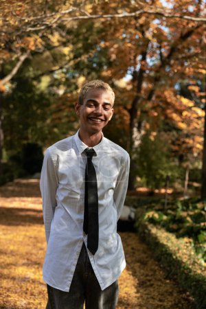Photo for Modern young man with urban look enjoying sunlight with closed eyes in the park in autumn, vertical photo - Royalty Free Image