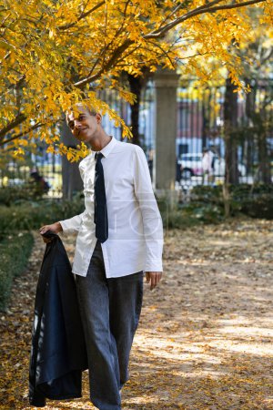 Téléchargez les photos : Jeune homme habillé de mode urbaine marchant dans le parc un jour d'automne - en image libre de droit