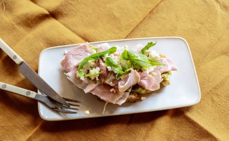 Photo for Close-up of a healthy bread toast with ham, cheese and rucula with cutlery - Royalty Free Image