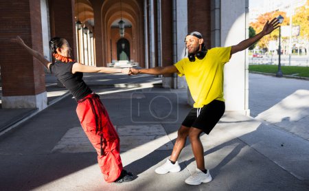 Téléchargez les photos : "Jeune couple multiracial dansant dans la rue, se tenant la main et souriant joyeusement." - en image libre de droit