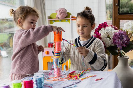 Téléchargez les photos : Deux petites filles jouant dans la salle de jeux avec des lacets colorés de l'artisanat - en image libre de droit