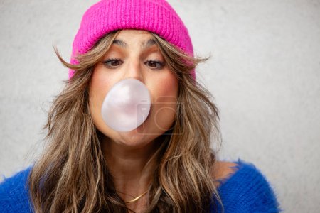 Photo for Portrait of a woman with a hat and a funny expression with a chewing gum bubble gum, white space - Royalty Free Image